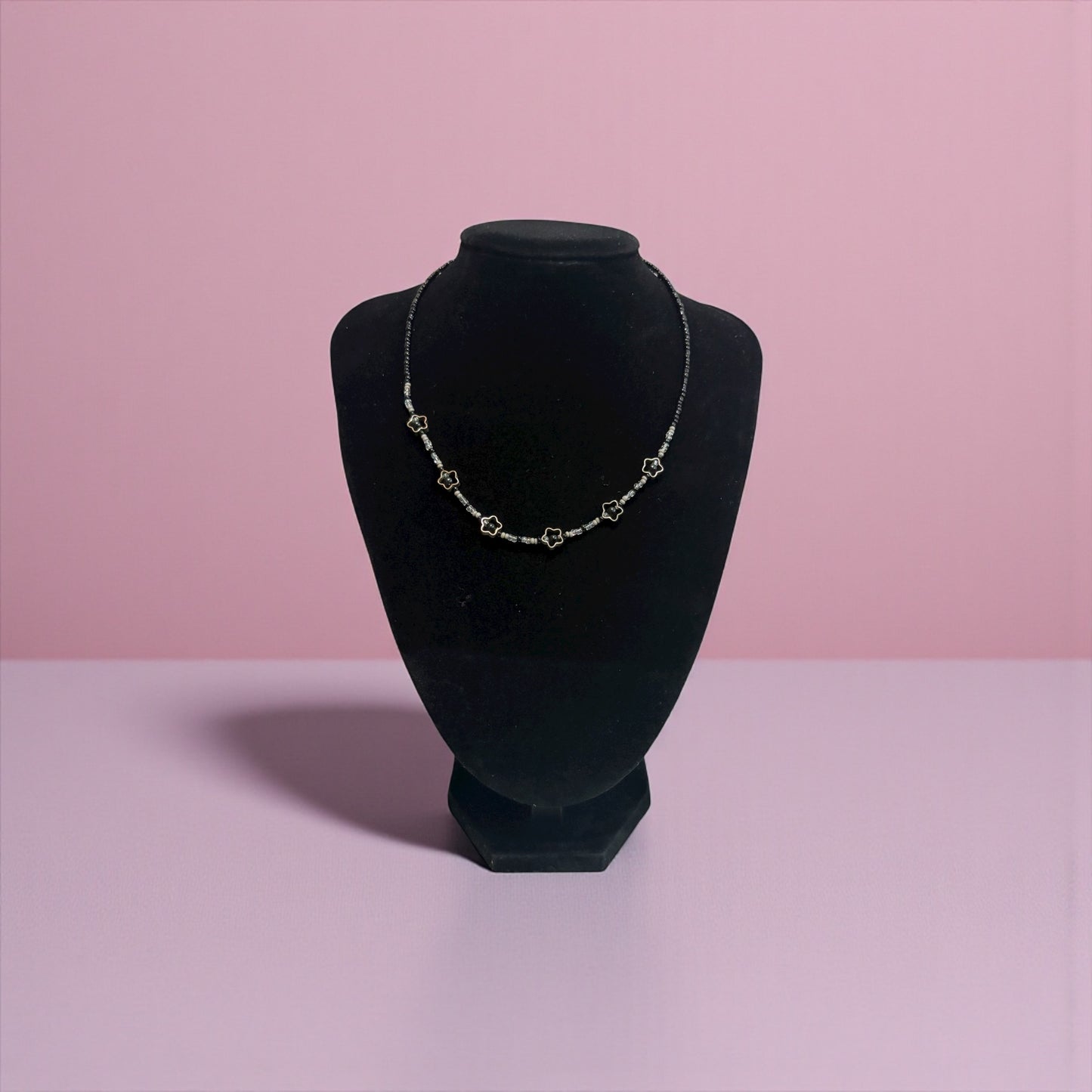 Necklace on a black velvet bust against a pink background