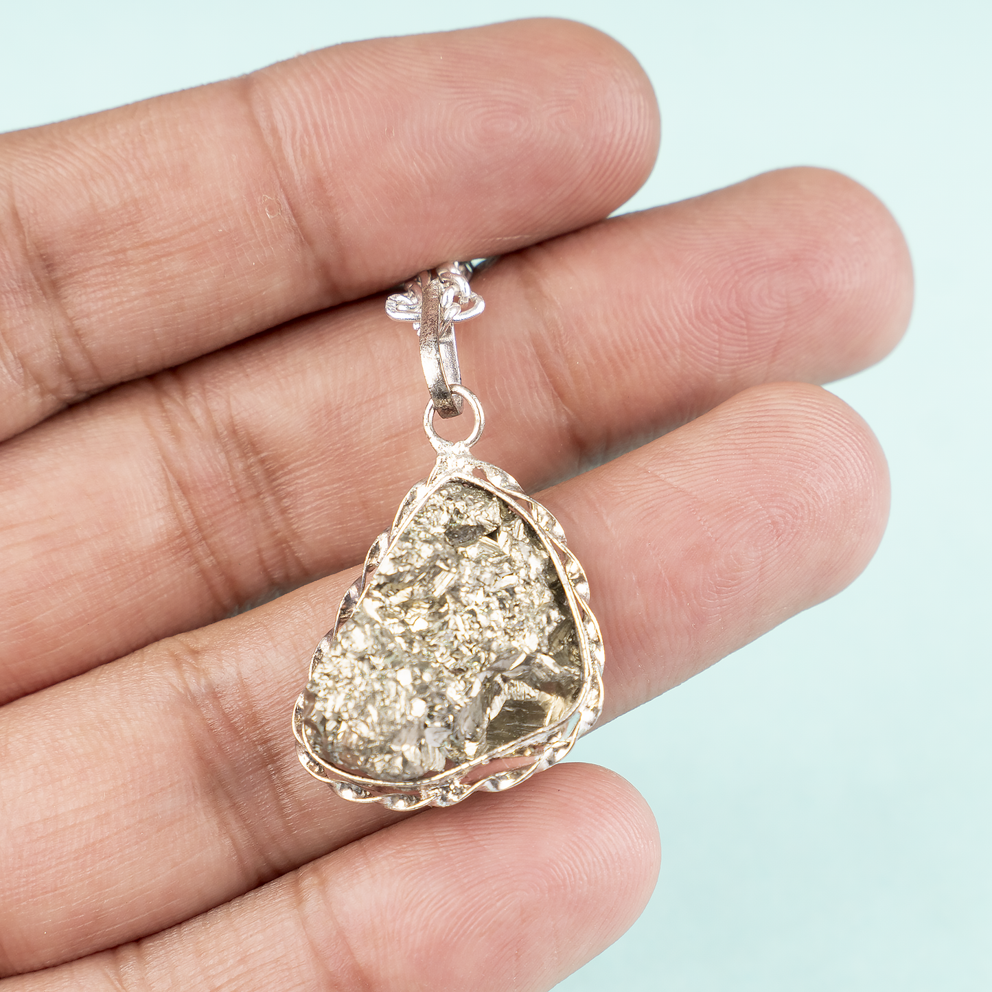 pendant held in a hand against a light blue background
