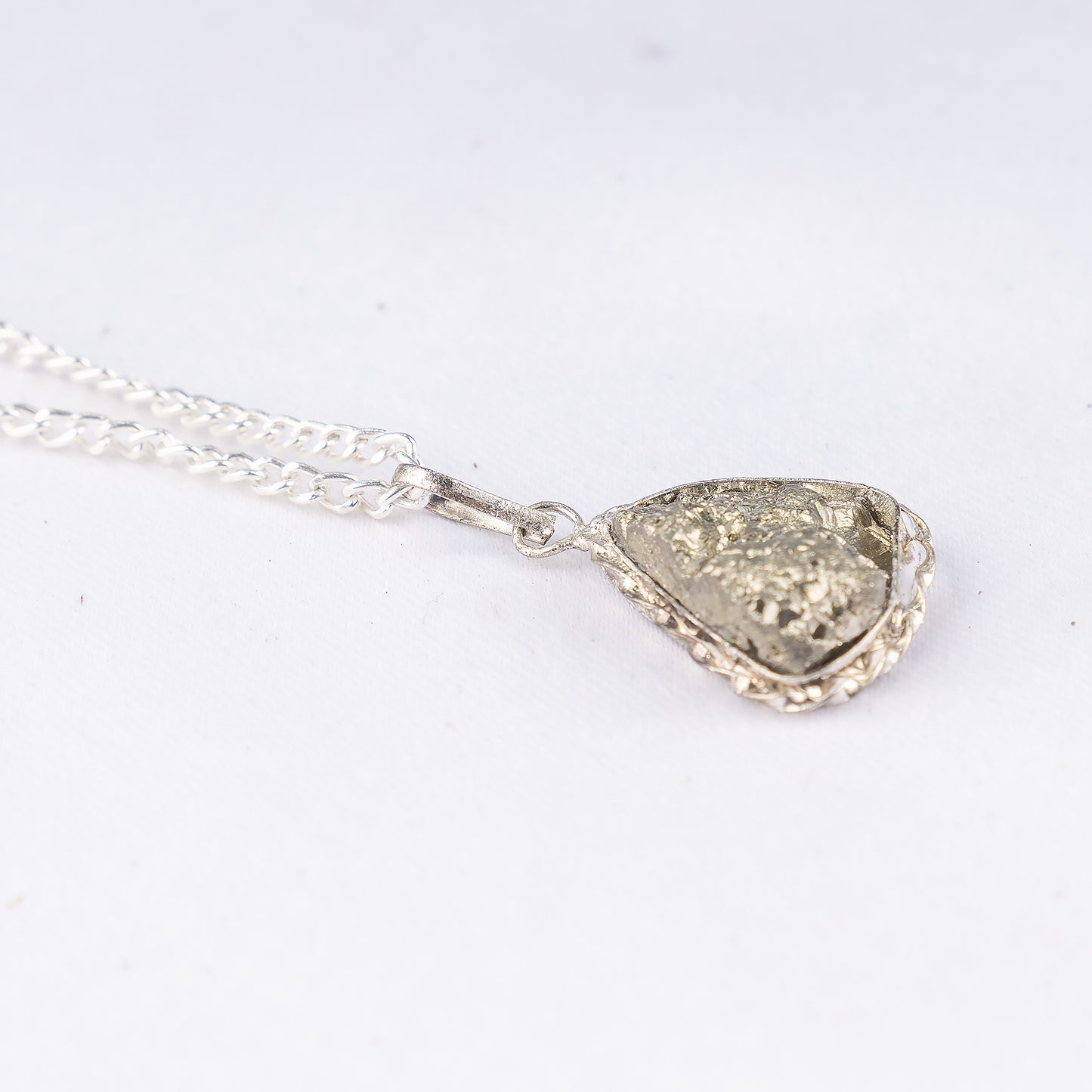 Silver necklace with a textured pendant on a white background