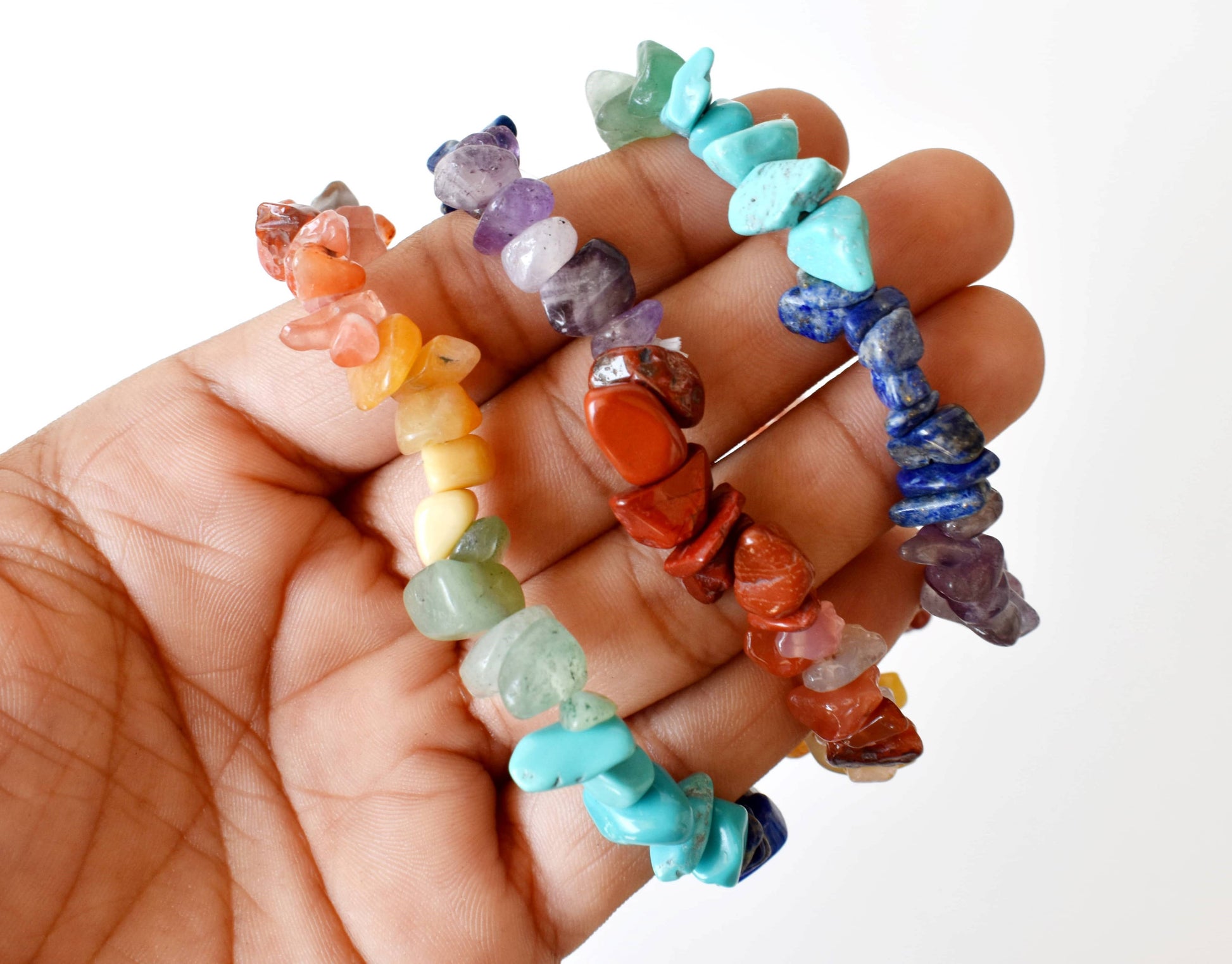 Hand holding a collection of colorful stone beads on a white background