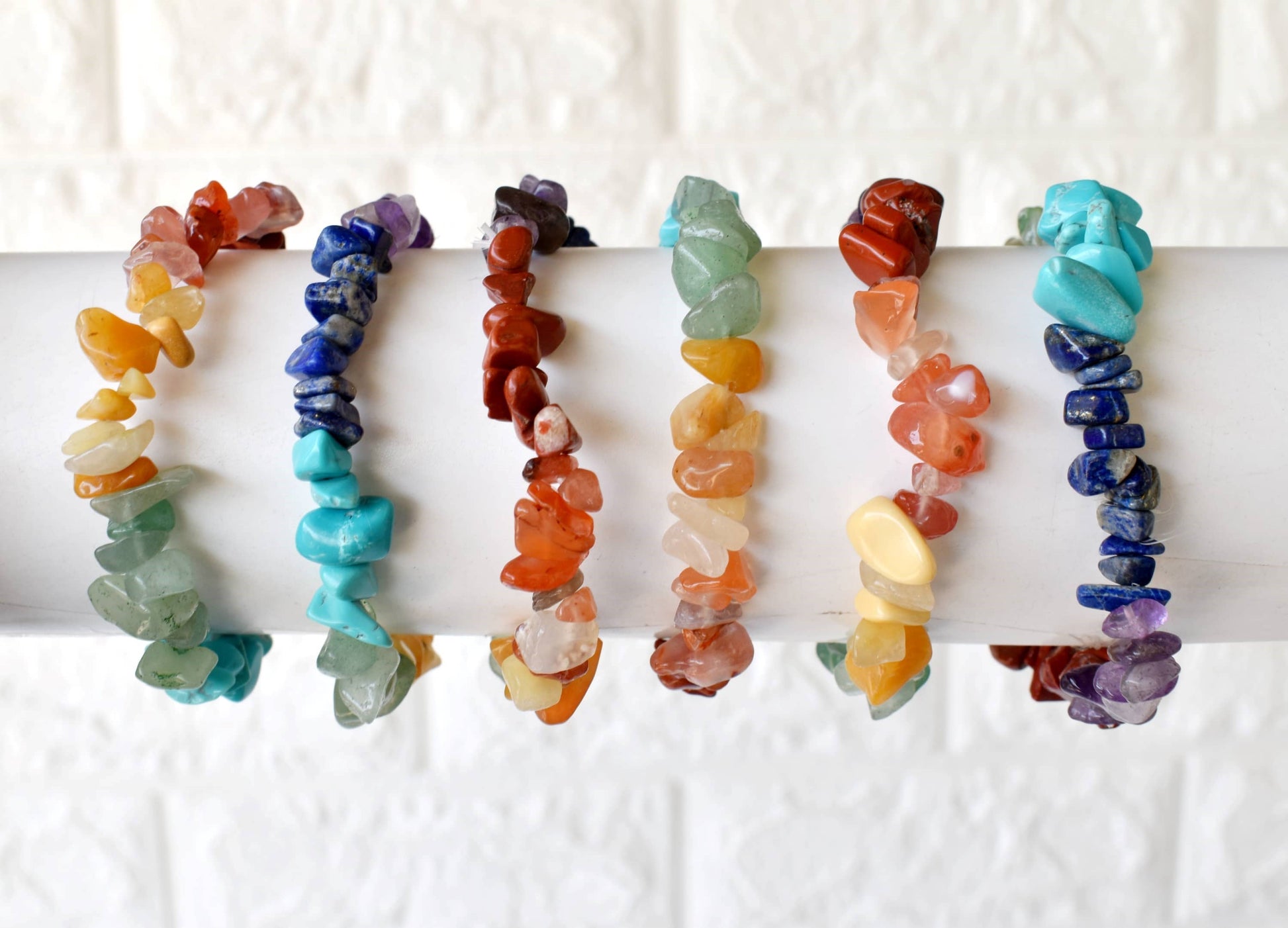 Set of colorful stone chip bracelets on a white background