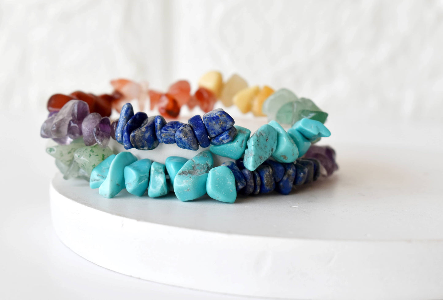 Stack of colorful stone bracelets on a white surface