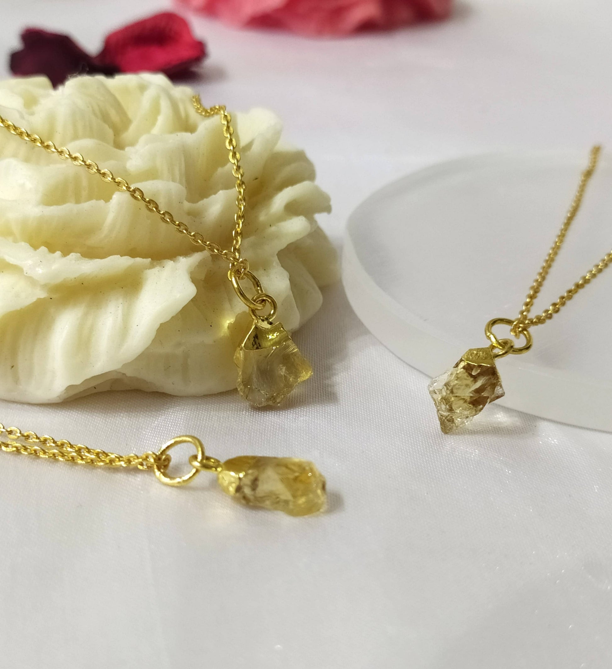 Gold necklaces with yellow gemstones on a white surface