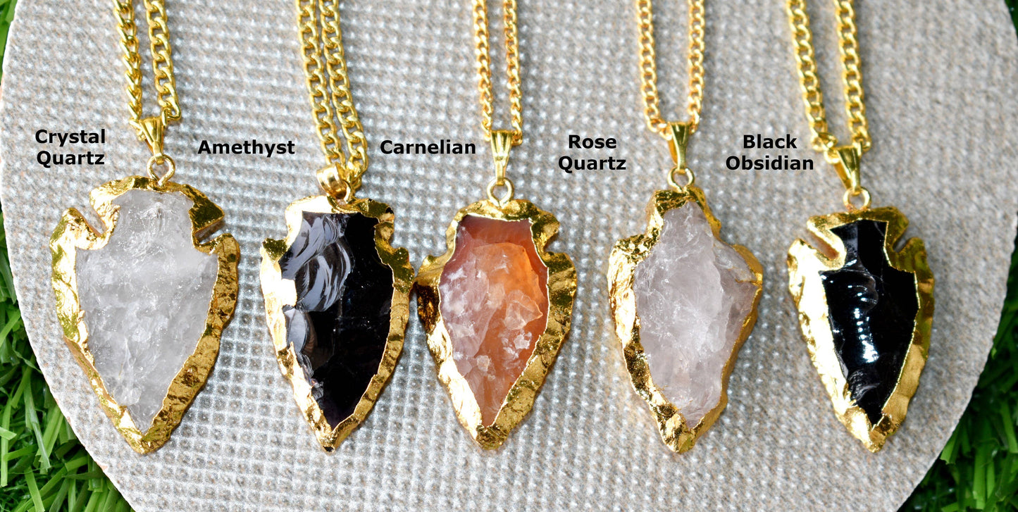 Five gold necklaces with arrowhead pendants on a white card, each labeled with a different stone type.