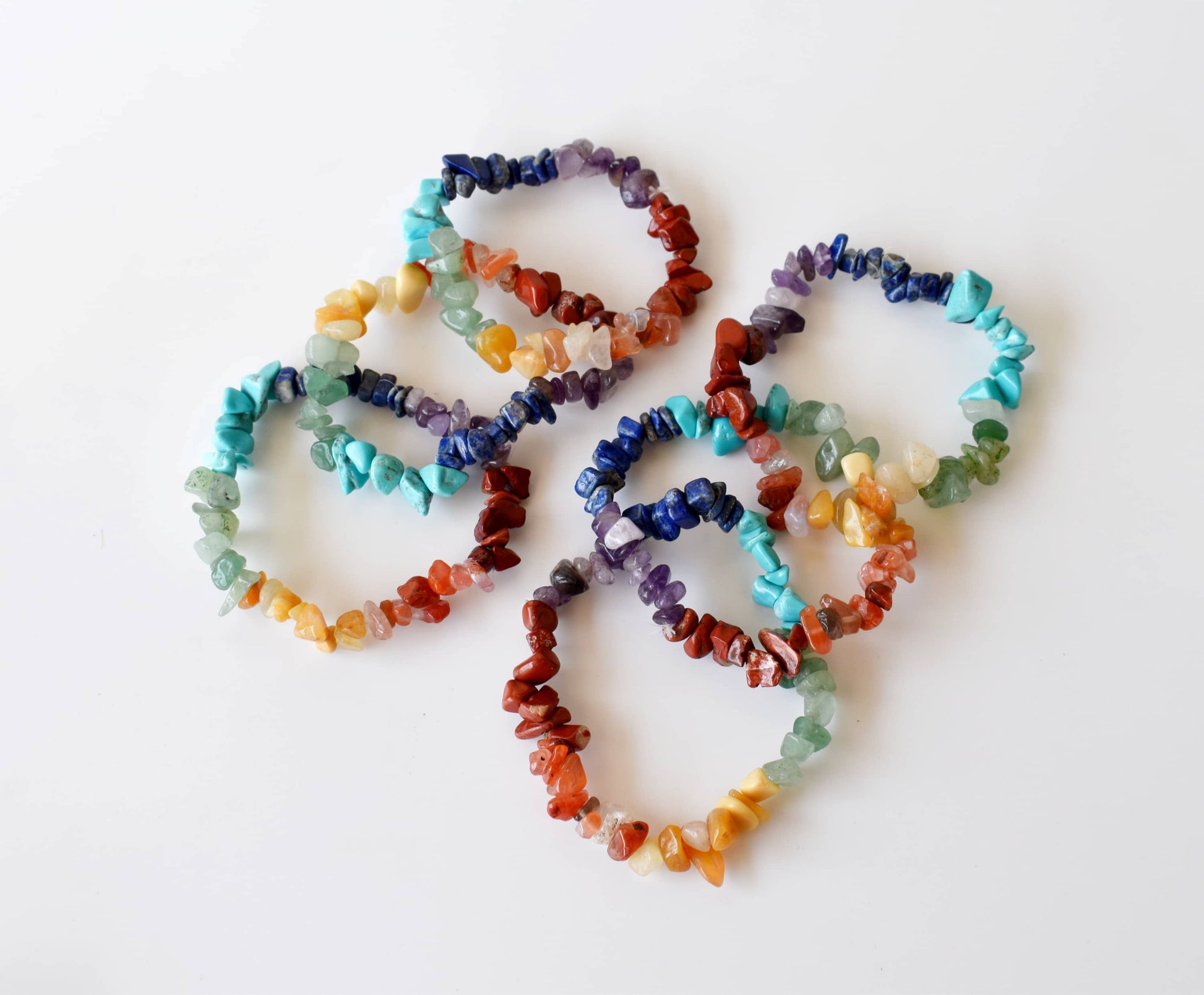Set of colorful stone bracelets on a white background