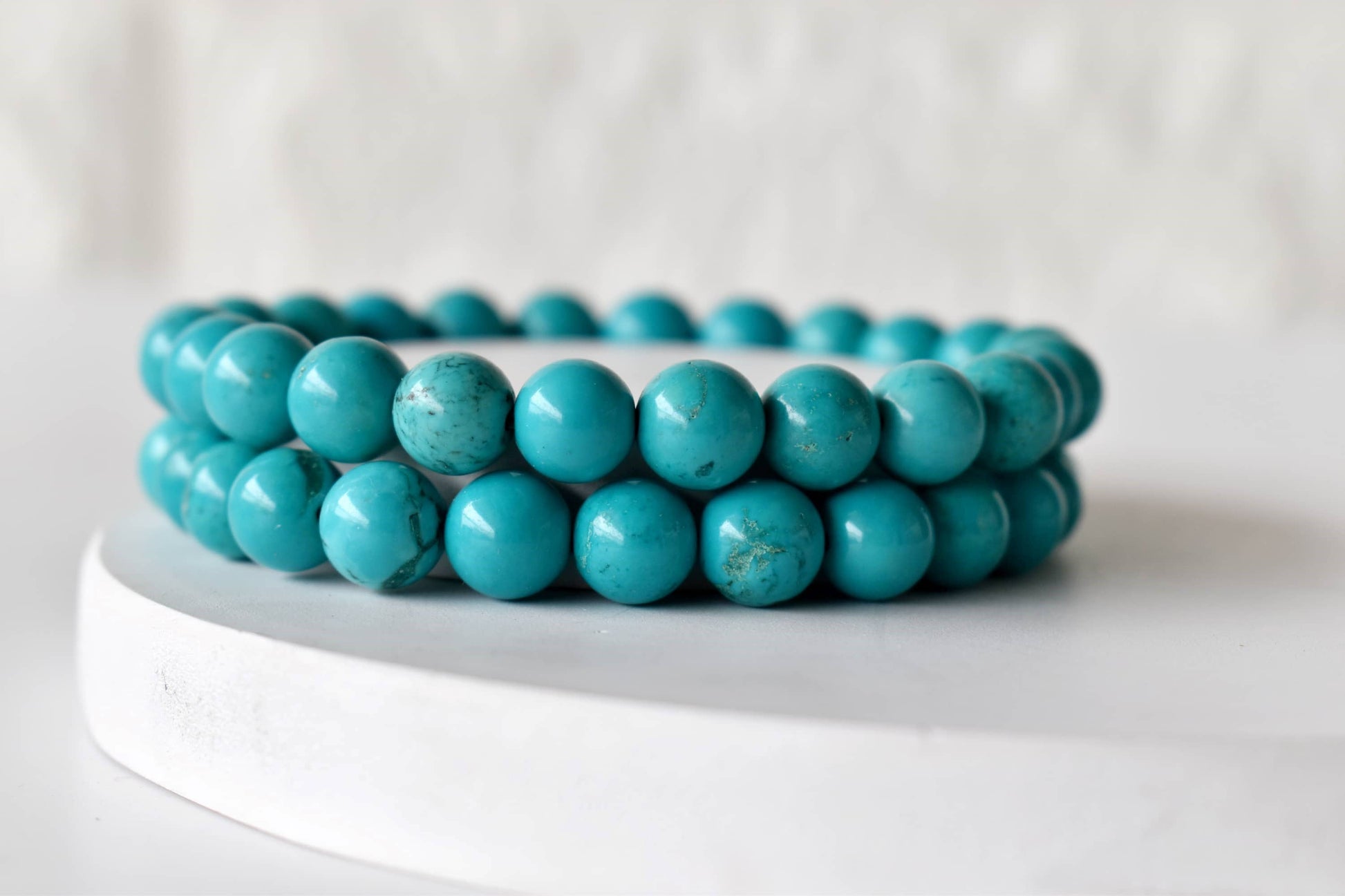 Turquoise beaded bracelets on a white stand with a white background