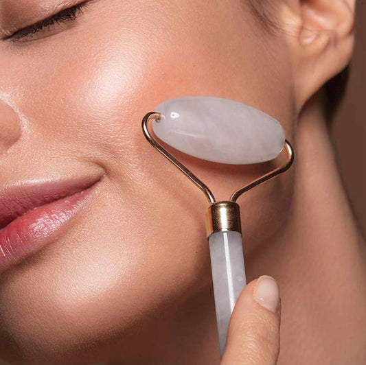 Woman using a jade roller on her face against a neutral background