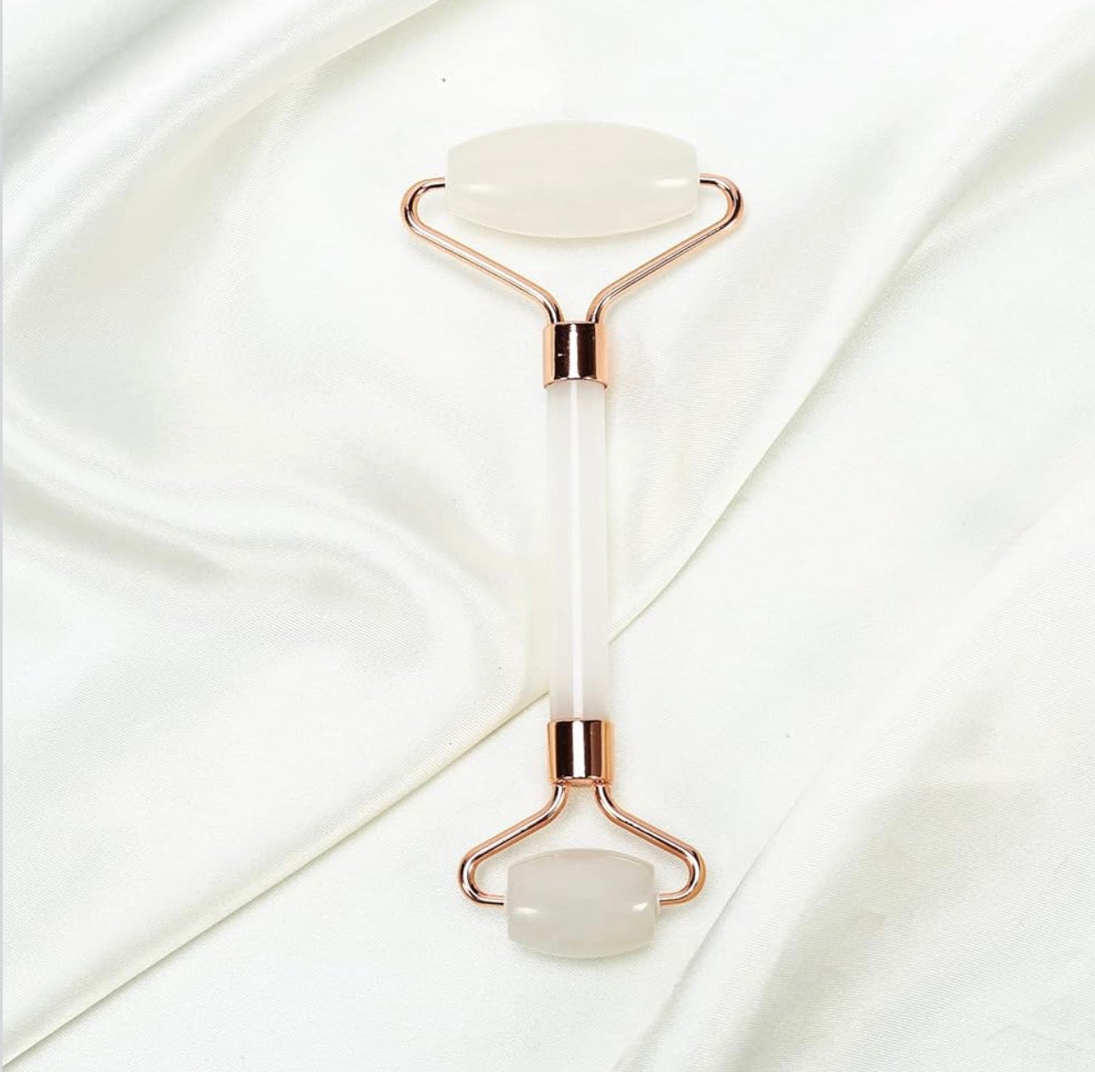White jade roller with rose gold frame on a white background