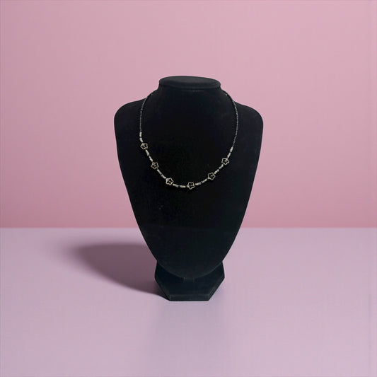 Necklace on a black velvet bust against a pink background