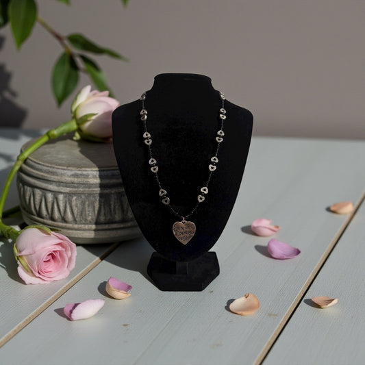 Necklace on a black bust with pink roses and petals on a light surface