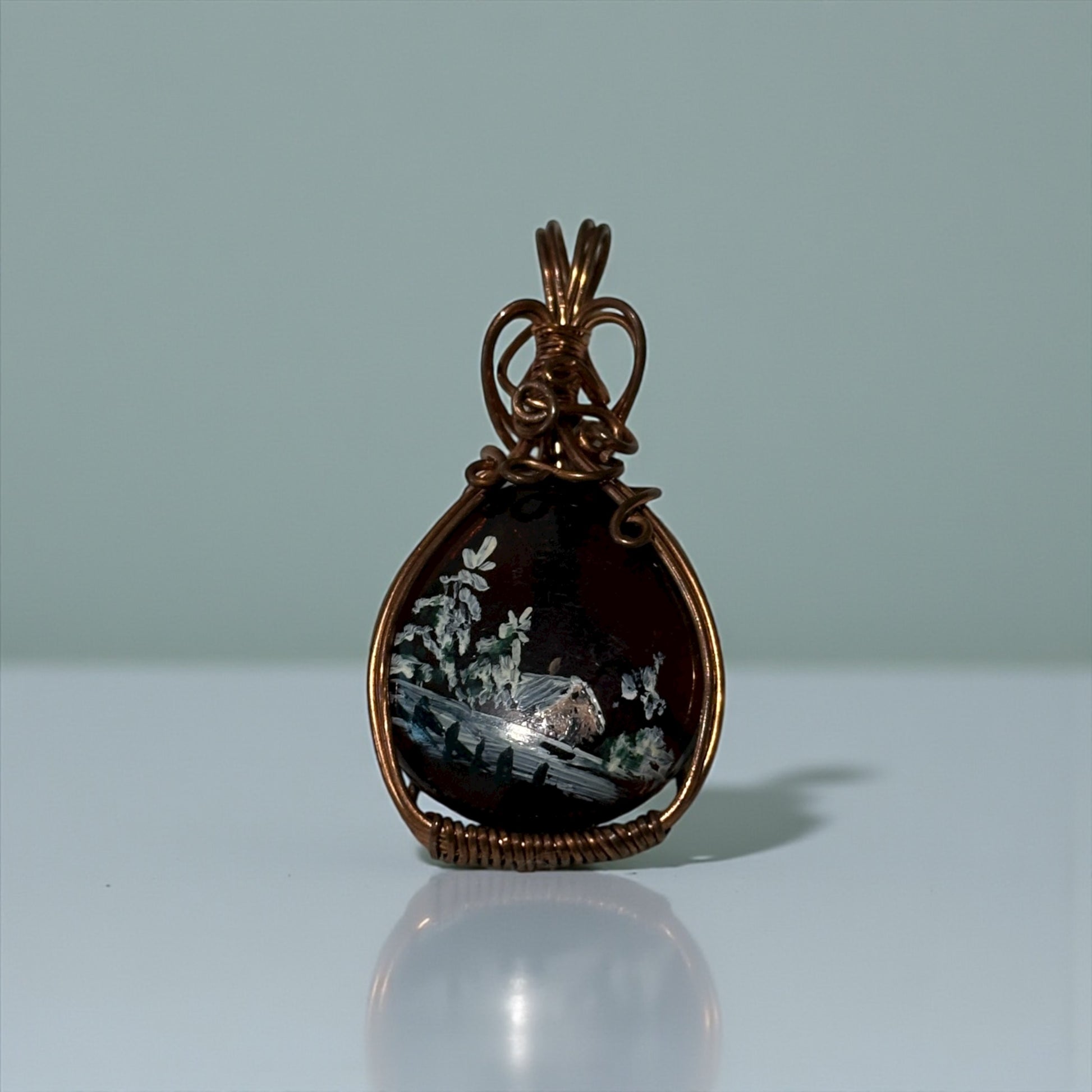 Bronze pendant with a scenic design on a light gray background