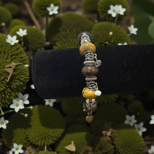 Beaded bracelet on a black stand with a natural green and white floral background