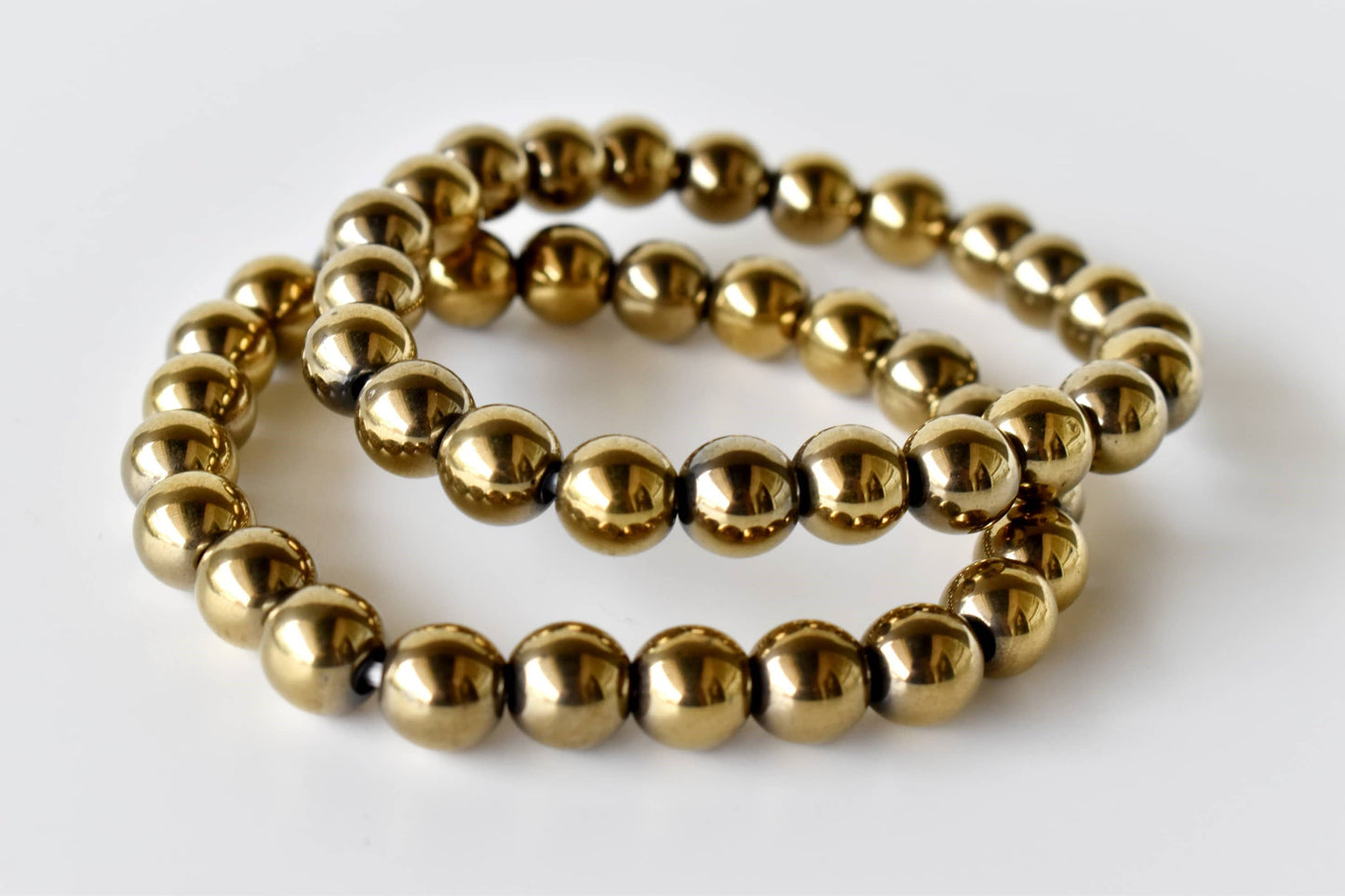 Two gold beaded bracelets on a white background