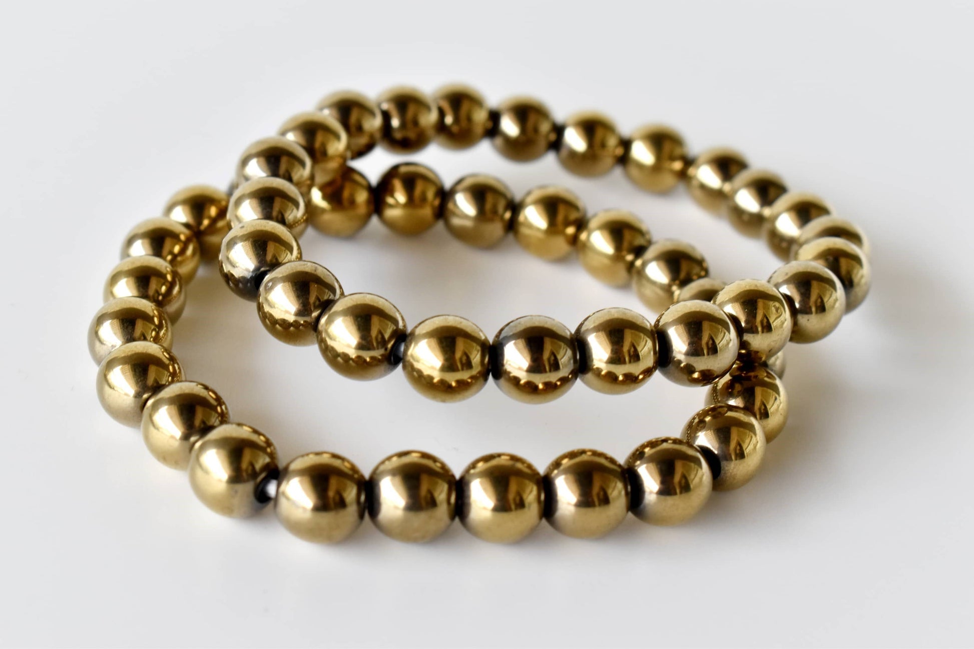 Two gold beaded bracelets on a white background