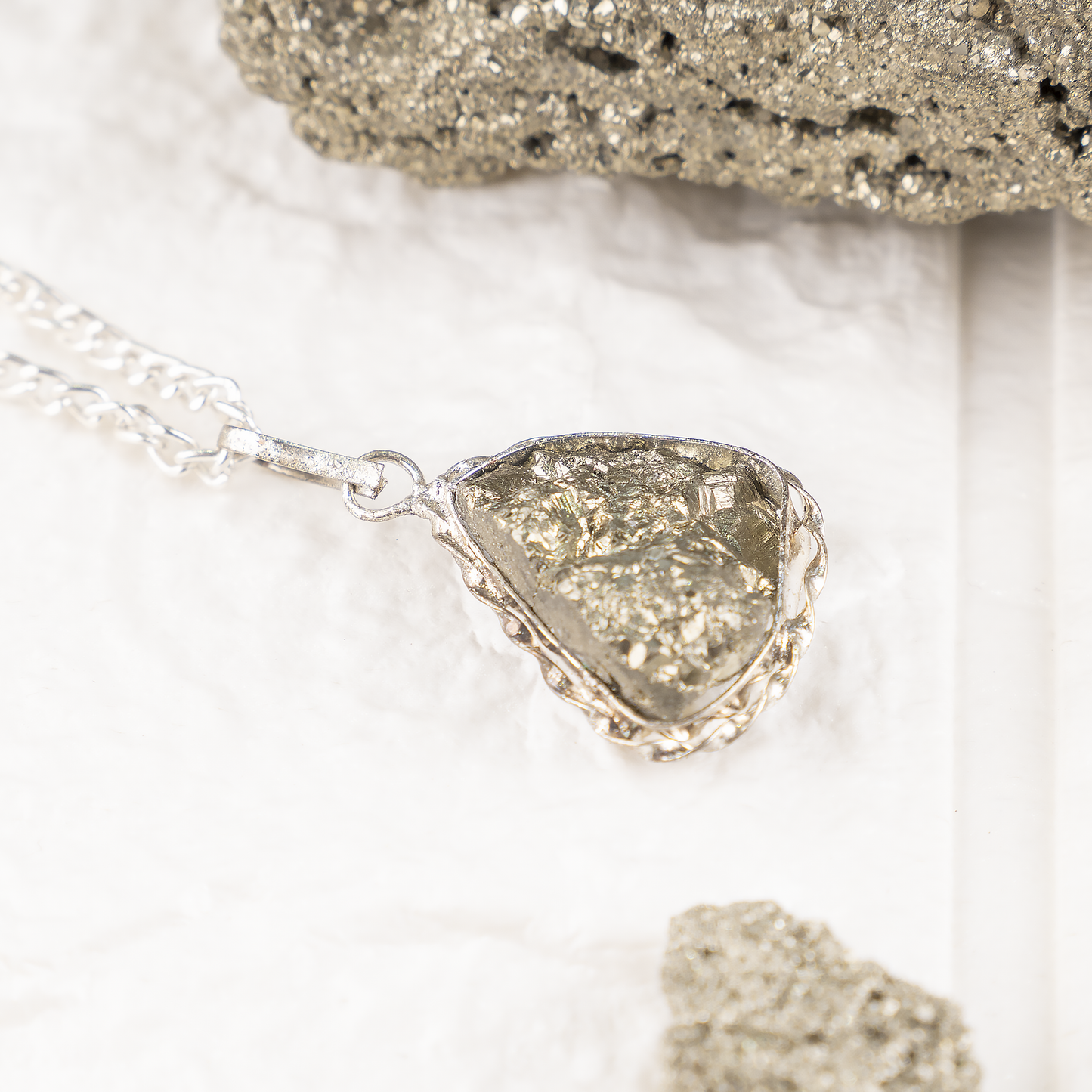 Silver necklace with a textured pendant on a light background