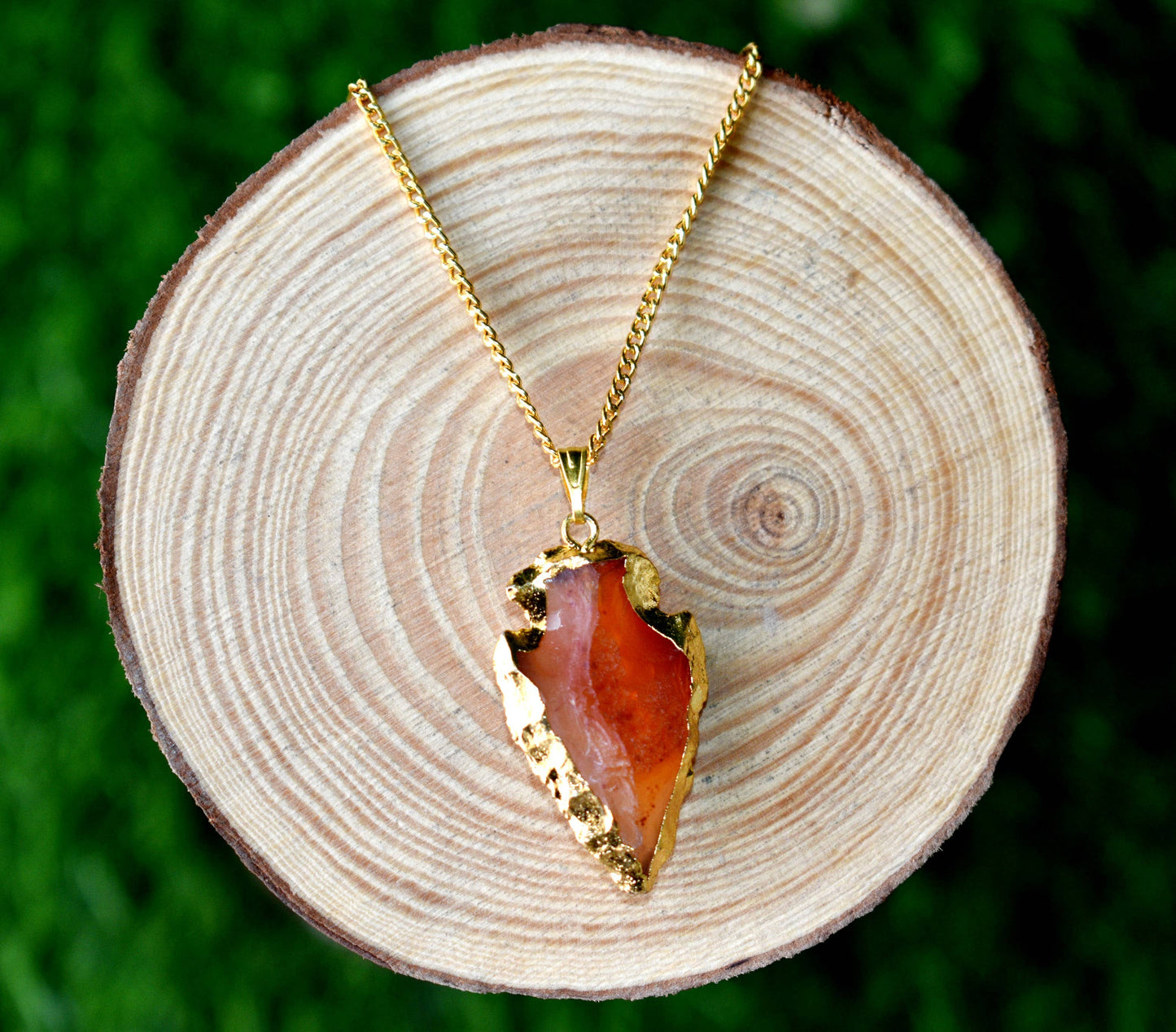 Gold necklace with a red stone pendant on a wooden surface