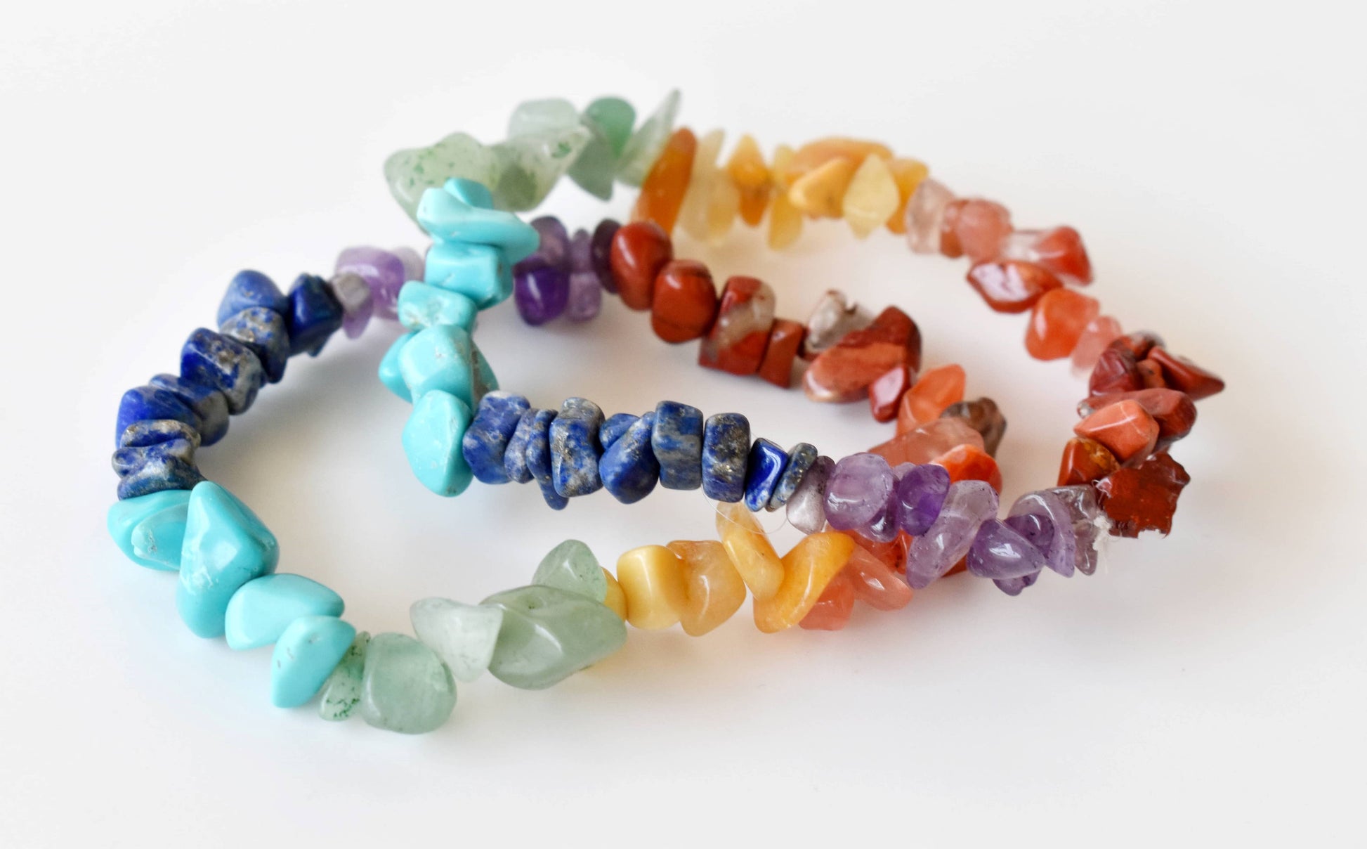 Set of colorful stone bracelets on a white background